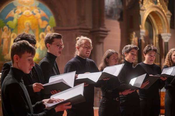 Quelle: Patrick Seeger Chorsänger:innen singen mit geöffneten Mappen auf den Altarstufen der Freiburger Johanneskirche